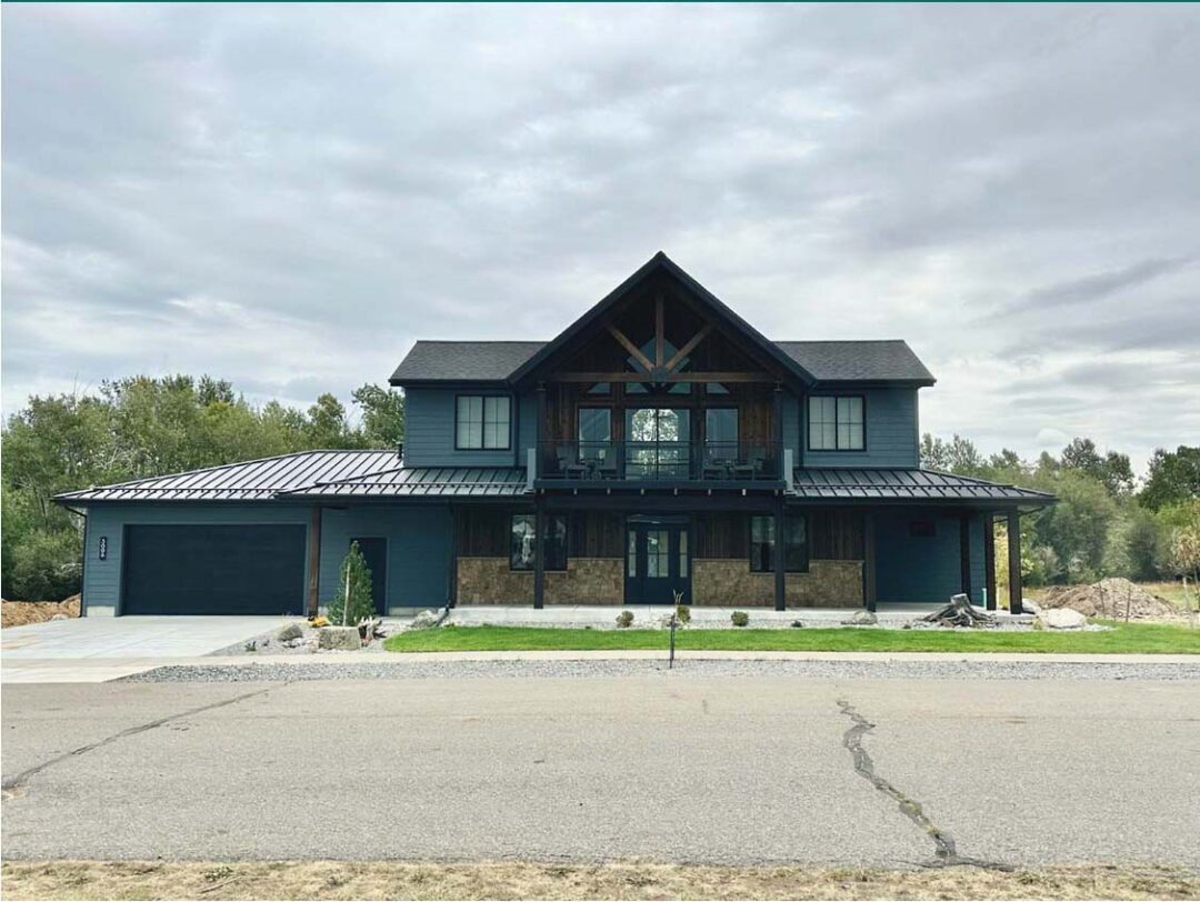 Modern two-story house with dark exterior, large windows, and a spacious front yard.