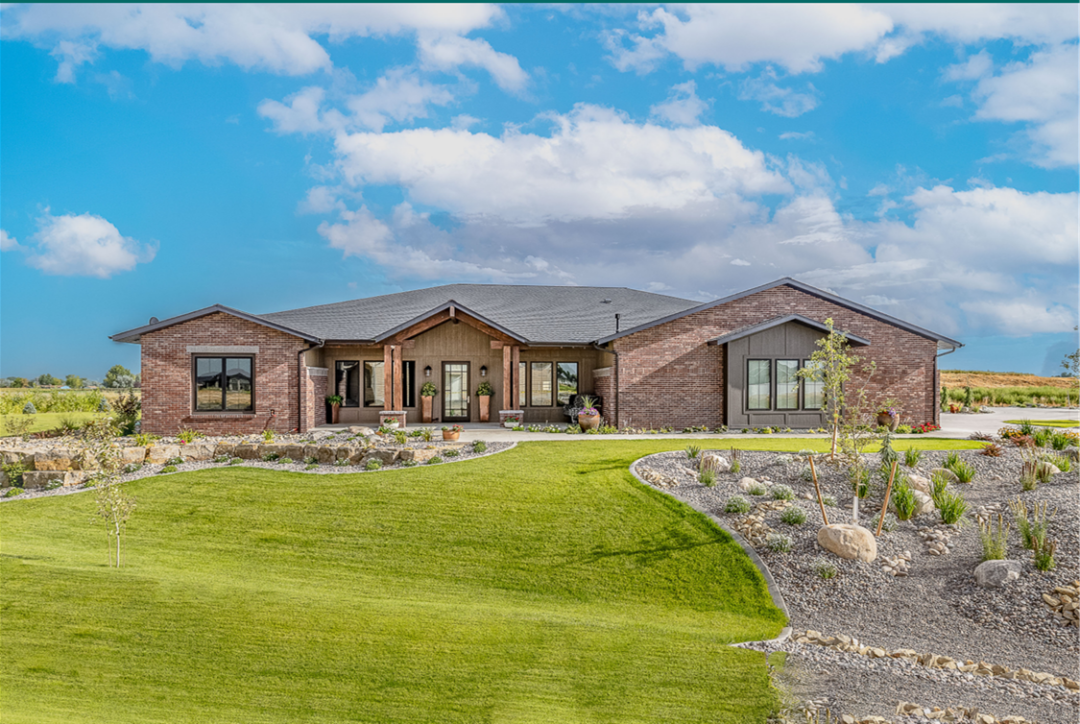 Modern brick home with landscaped yard and clear blue sky.