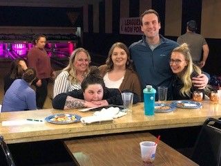 A woman and three men smiling at a table during a social event at the Home Builders Association of B.